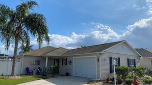 A single-story house with a garage, a covered porch, and a well-maintained lawn. - 2351 Bayberry Ct (The Villages)