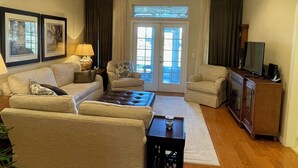 A living room with a sofa, armchairs, a coffee table, a TV, and a ceiling fan. - 1504 Wresh Way (The Villages)