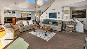 A spacious living room with a large sofa, a coffee table, and a dining area with a kitchen in the background.