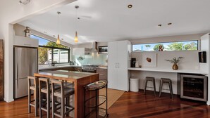 A modern kitchen with a central island, stainless steel appliances, and a large window providing natural light.