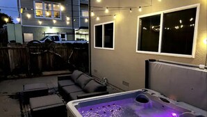 A backyard with a hot tub, outdoor seating, and string lights. - Game room, hot tub, 20 min to SF, beach 1 block away (Pacifica)