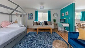 A well-lit room with a bed, a sofa, a desk, and a computer. There are curtains, a clock, and a plant. - Game room, hot tub, 20 min to SF, beach 1 block away (Pacifica)