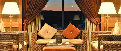 A room with a sofa, two armchairs, a coffee table, and a view through a window with curtains.
