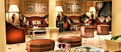 A luxurious lobby with plush seating, a central coffee table, and framed artwork on the walls.