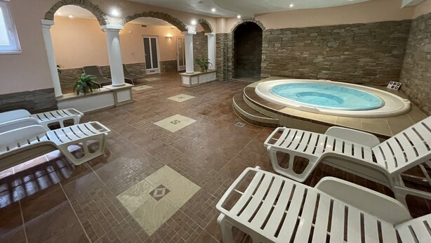 Un área de spa con bañera de hidromasaje, sillones reclinables y paredes de piedra.