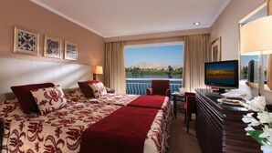Hotelkamer met een bed, een bureau met een computer, een televisie en uitzicht op een waterlichaam.