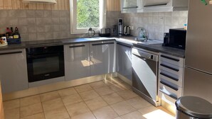 Una cocina moderna con electrodomésticos de acero inoxidable, un ventanal y paneles de madera en las paredes.