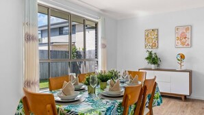 A dining area with a table set for six, chairs, a cabinet, and a window with curtains. - Spacious Newly Furnished 4BD Family Retreat (Heathwood)