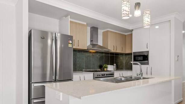 A modern kitchen with a stainless steel refrigerator, a built-in oven, and a large island with a sink. - Spacious Newly Furnished 4BD Family Retreat (Heathwood)