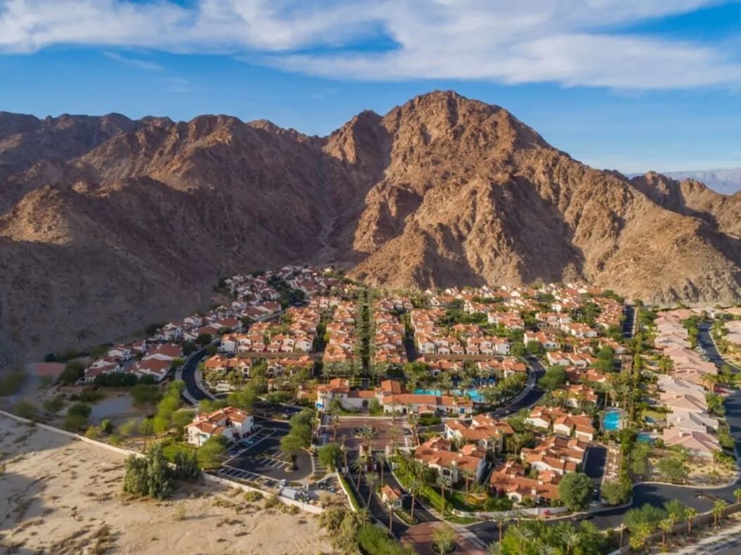 A residential area with houses, roads, and mountains in the background.