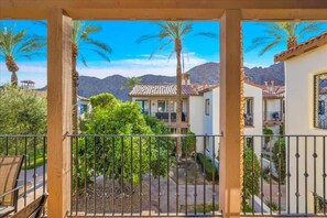 Un balcón con vistas a una zona residencial, que incluye casas y palmeras.