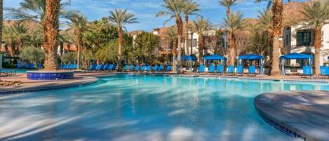 Area piscina con poltrone da relax blu e palme.