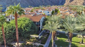 A residential area with houses, palm trees, and mountains in the background.