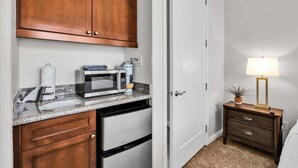 A compact kitchen with a microwave, toaster, and coffee maker on a granite countertop.