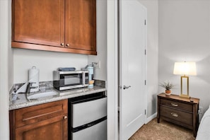A compact kitchen with a microwave, toaster, and coffee maker on a granite countertop.