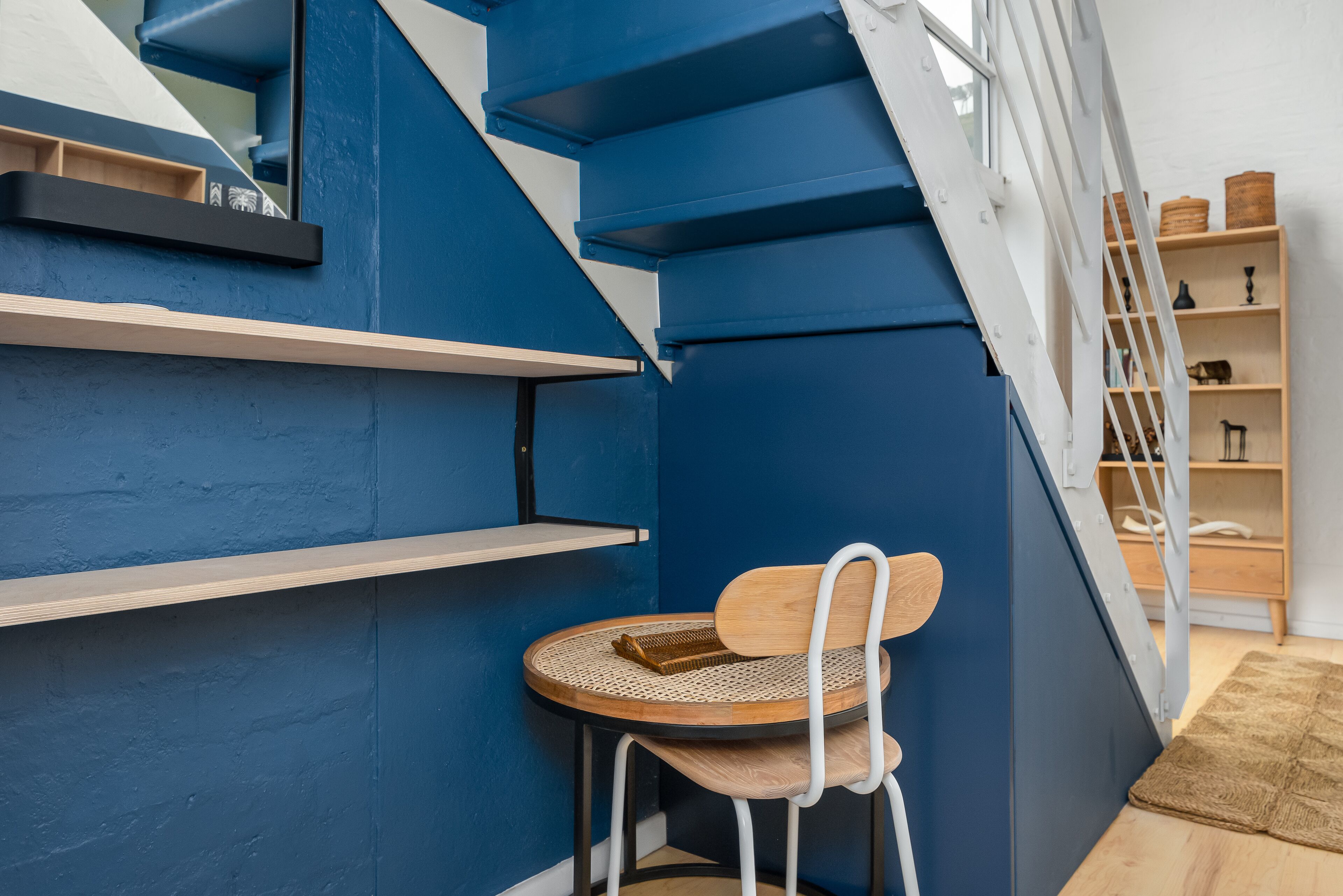 A corner with a blue wall, a wooden chair, and a small round table.
