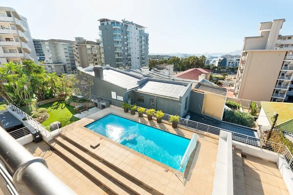 Enjoy a refreshing swim in the rooftop pool surrounded by lush greenery and modern architecture.