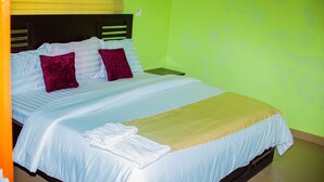 A bed with white bedding, two red pillows, and a beige blanket. - Omooke Hotel (Ibadan)