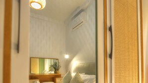 Et soveværelse med seng, sengebord, lampe og et spejl.