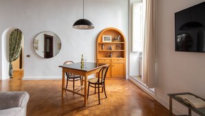 A dining area with a wooden table and chairs, a round mirror, a hanging pendant light, and a wooden cabinet with shelves. - NAVONA ART GALLERY APARTMENT (Roma)