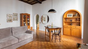 A living room with a grey sofa, wooden dining table, and a wooden cabinet with shelves. - NAVONA ART GALLERY APARTMENT (Roma)