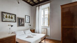 A bedroom with a wooden floor, a bed with white linens, a wooden wardrobe, and two framed artworks on the wall. - NAVONA ART GALLERY APARTMENT (Roma)