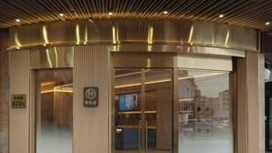 A hotel entrance with a modern design, featuring a curved facade, glass doors, and a visible reception desk inside. - HanTing Hotel (Shanghai Jing'an Daning Park) (Shanghai)