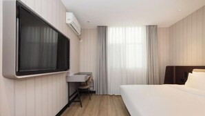 A hotel room with a bed, a desk, a chair, a TV mounted on the wall, and a window with curtains. - HanTing Hotel (Shanghai Jing'an Daning Park) (Shanghai)