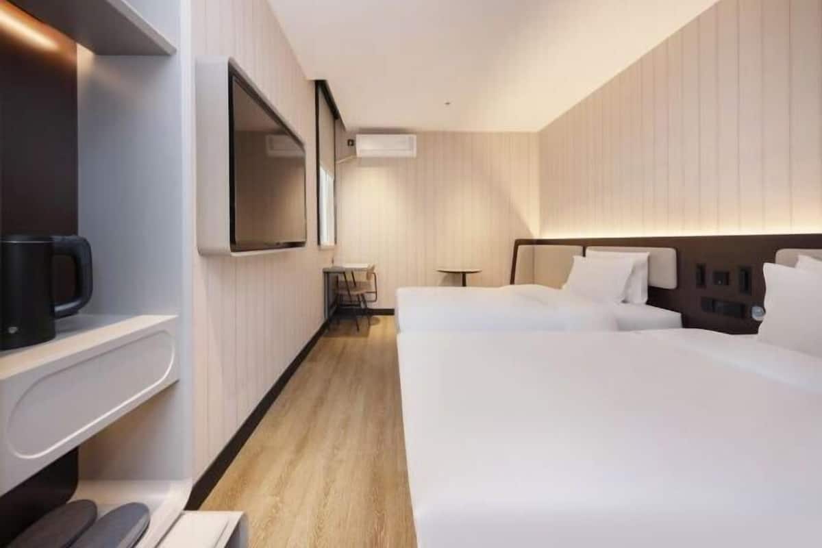 A modern hotel room with a large bed, a desk, a chair, and a flat-screen TV.