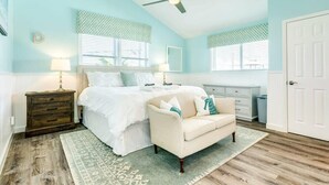 Un dormitorio con cama, mesita de noche, cómoda, ventilador de techo y una puerta.
