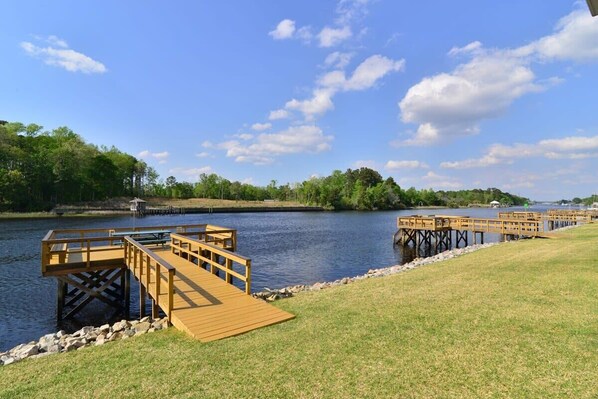 A riverside dock with wooden walkways and a grassy bank.