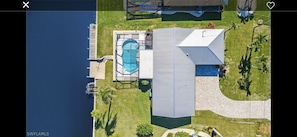 Vue aérienne d’une propriété dotée d’une piscine, d’un patio couvert et d’un grand bâtiment à toit en pente.