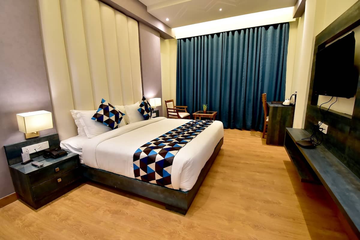 Habitación de hotel con una cama grande, mesitas de noche, un televisor y un escritorio con una silla.