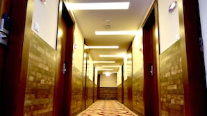 A hotel hallway with a patterned carpet, wooden doors, and recessed lighting. - HOTEL CENTELLA  (Gwalior)