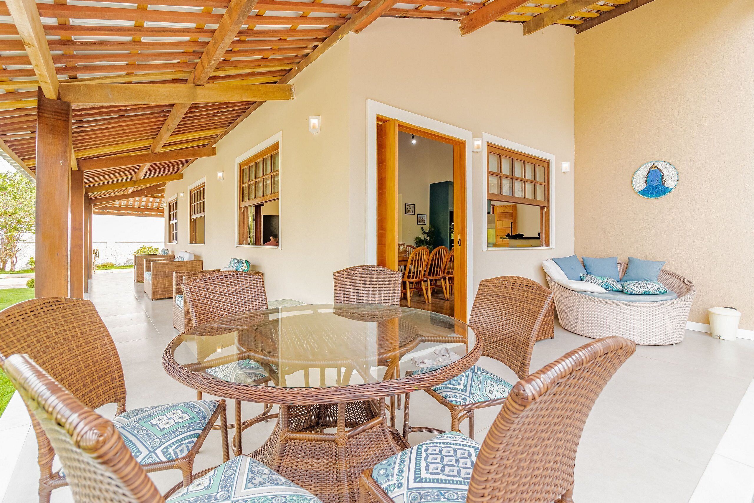 A covered outdoor area with wicker furniture and a glass-top table.