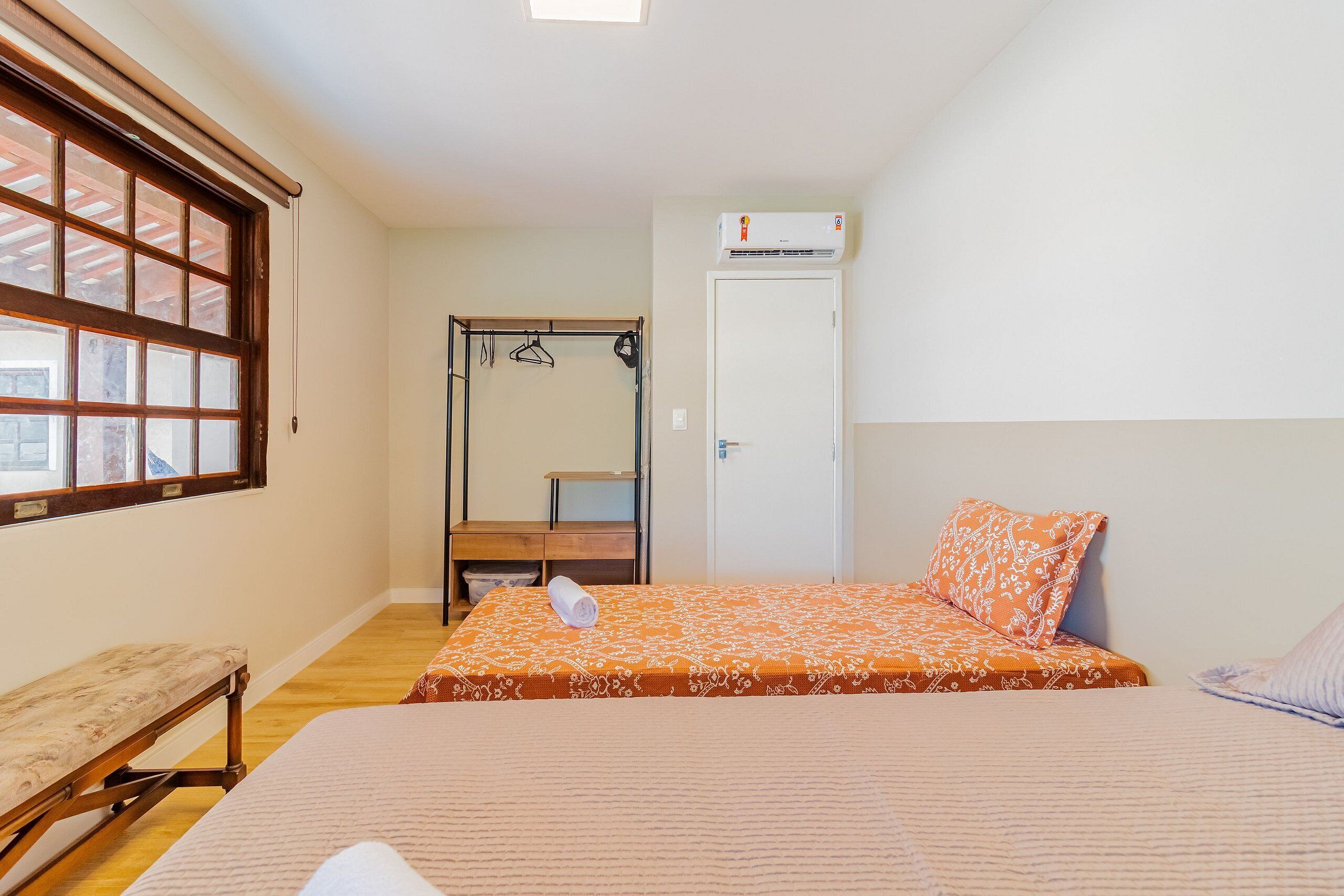 Ein Schlafzimmer mit einem Bett, einer Bank, einem Kleiderschrank und einem Fenster.