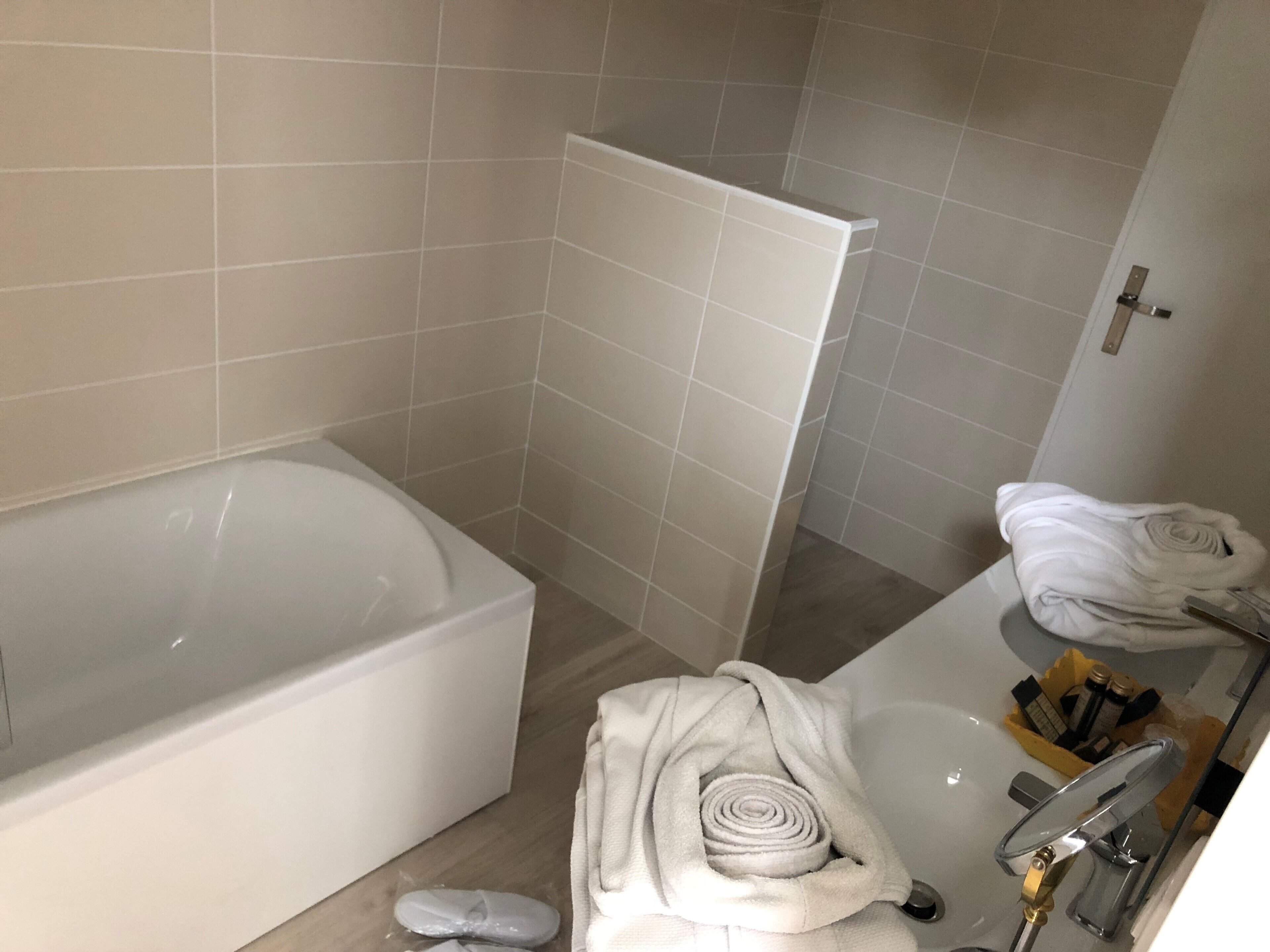 A bathroom with a bathtub, a mirror, and towels.