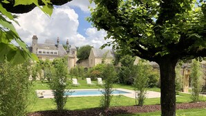 A well-maintained garden with a swimming pool, surrounded by manicured lawns and trees.