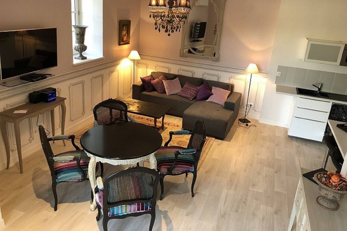 Un salon moderne comprenant un canapé, des fauteuils, une table à manger, un téléviseur et un coin cuisine.
