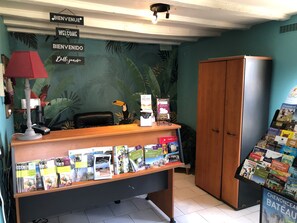 A reception desk with a tropical mural, a red lamp, a telephone, and a display of brochures.