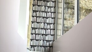 A staircase with wooden steps leading to a bookshelf filled with books.