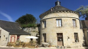 A stone building with a round tower, a wooden fence, and potted plants.