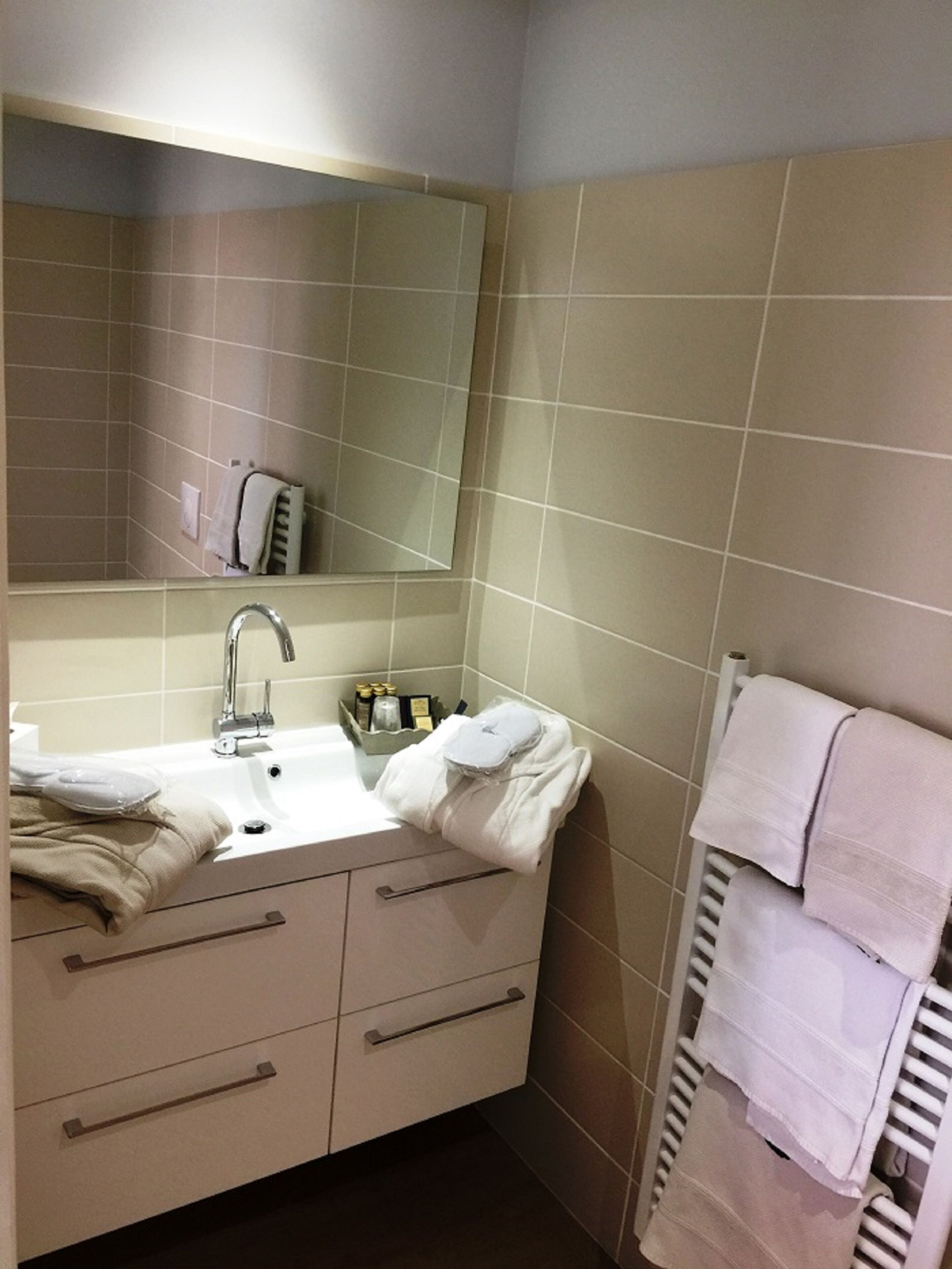 Een badkamer met wastafel, spiegel, handdoekhouder en radiator.