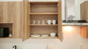 A kitchen with wooden cabinets, a microwave, and a stainless steel range hood. - House Valencia 1 (Flores)