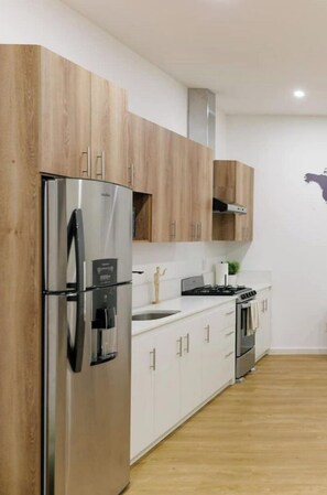 Enjoy cooking in this well-equipped kitchen with a stainless steel refrigerator, oven, and ample cabinetry.