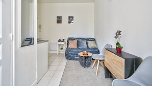 A compact living space with a sofa, a small table, a cabinet, and a potted plant. - Magnificent studio just outside Paris (Clichy)