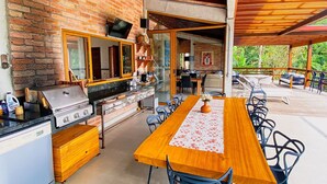 Cuina exterior amb una barbacoa, taula de menjador i cadires.