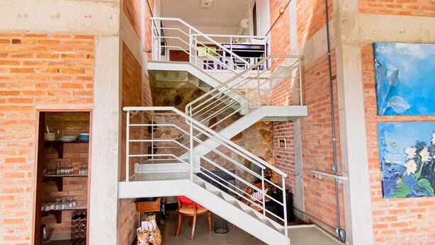 Un interior de diversos nivells amb una escala, una zona de menjador i un quadre a la paret.