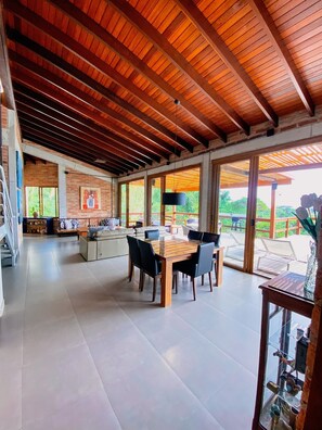 A spacious living area with a high ceiling, a dining table, and a view of the outdoors. - Paraiso em Juquehy (São Sebastião)