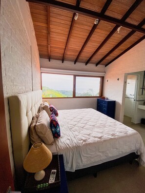 Un dormitorio con una cama grande, una ventana y techo de madera.